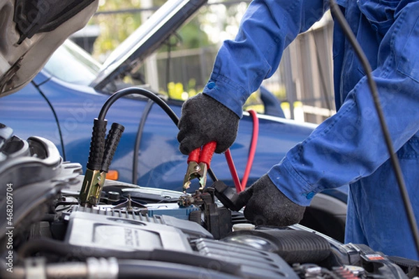 Obraz Close up of hand mechanic car service battery with electricity through jumper cables. Service work by professional technicians concept.