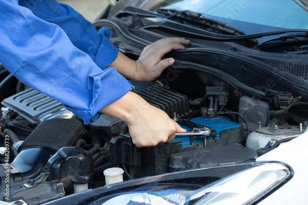 Fototapeta Professional Asian handsome mechanic in uniform are working in auto service. Close up hands mechanic car repair and maintenance at workshop garage concept.