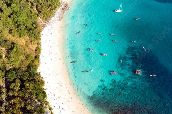 Obraz View from above, stunning aerial view of a white sand beach bathed by a turquoise, clear water. Tropical beach with some long tail boats and relaxed tourists. Freedom beach, Phuket, Thailand.