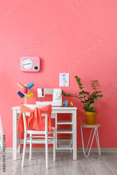Fototapeta Modern tailor's workplace with sewing machine and threads near pink wall
