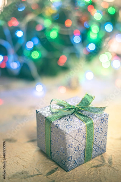 Fototapeta Beautiful Christmas gift boxes. Colored Presents for Birthdays. Boxes with gifts tied with ribbon and bows background. craft paper present box. Christmas tree toys and lights. happy new year 2022.