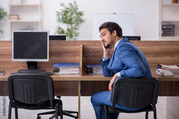 Fototapeta Young male employee sitting at workplace
