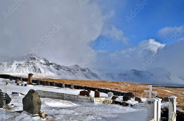Obraz cemetery in Budir stone fence and tombstones in the background snow-capped and misty mountains, Iceland