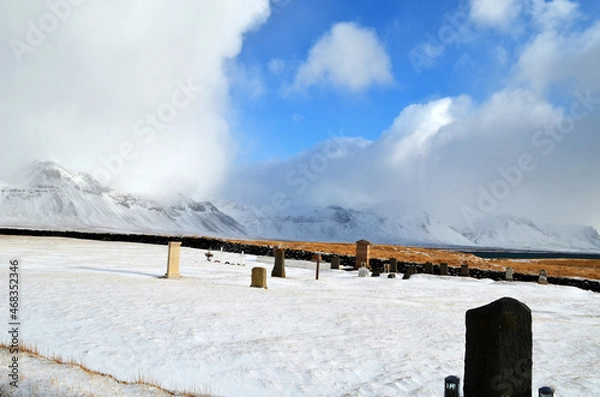 Obraz cemetery in Budir stone fence and tombstones in the background snow-capped and misty mountains, Iceland