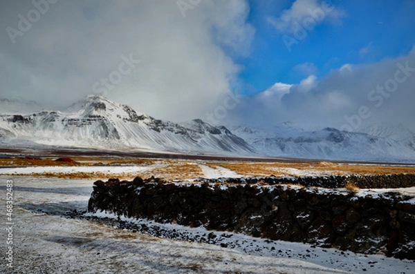 Obraz stone fence and in the background snow-capped and misty mountains in Budir, Iceland