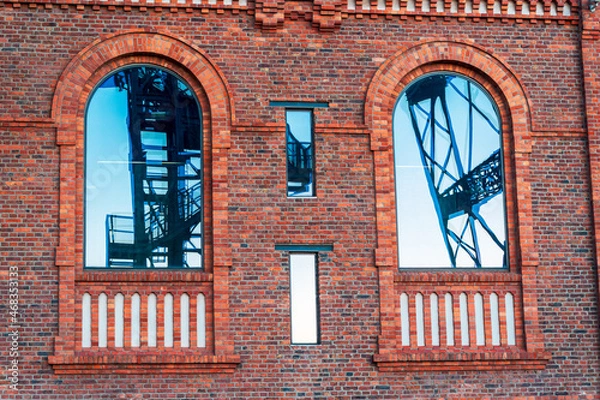 Fototapeta Glossy windows in the engine room building in former coal mine in Katowice, Silesia, Poland - present Silesian Museum. Reflection of the mine shaft tower.
