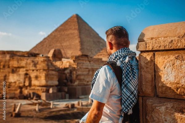 Obraz A tourist man stands with his back to the camera and looks at the pyramids. Meditation near the pyramids in Cairo, Egypt

