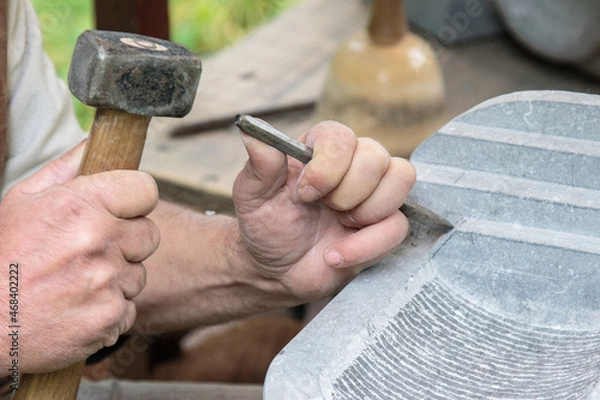 Fototapeta closeup of hands of a sculptor carving a stone slab with a chisel