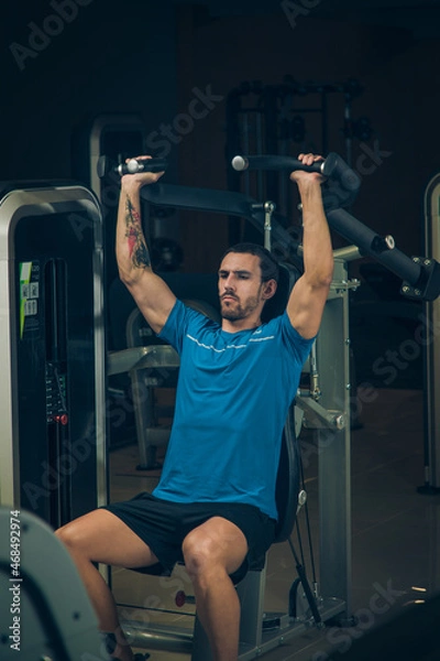 Obraz young man exercising lats on machine