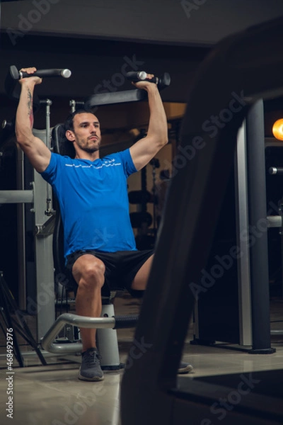 Obraz young man exercising lats on machine