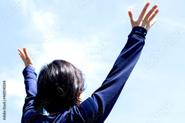 Fototapeta 大空の下で若い女性が手を広げて見上げている