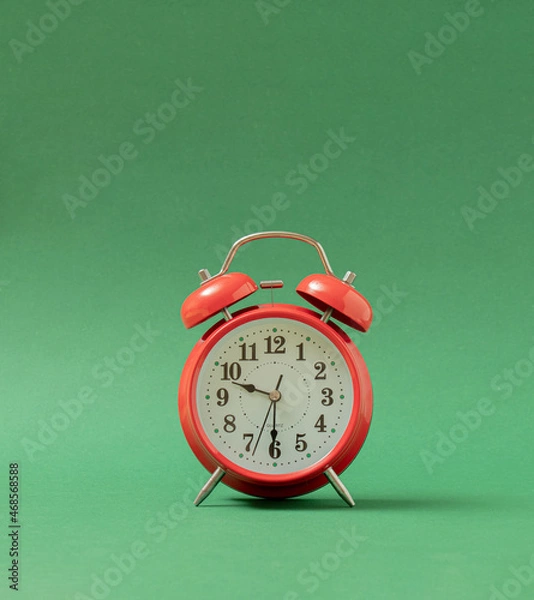 Fototapeta old red vintage table clock against pastel green background with shadow. Retro abstract art
