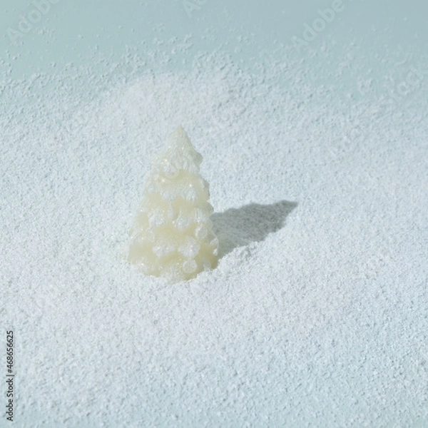 Fototapeta Christmas tree with sparkle in snow on ice blue background. Winter holidays and New Year layout.