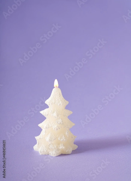 Fototapeta Christmas tree shiny candle with flame against pastel purple background. Winter holidays and New Year idea.
