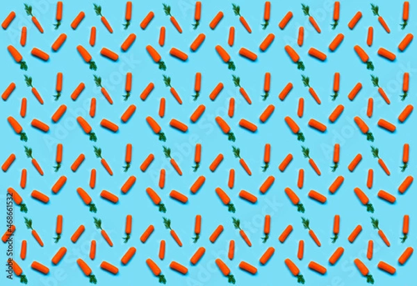 Fototapeta Pattern of carrots on blue background. Design for Easter or wrapping paper. Creative copy space