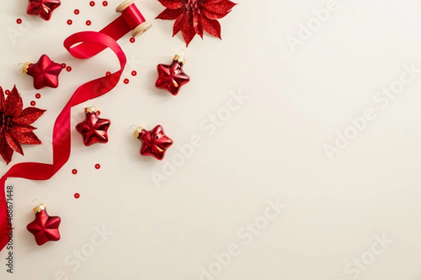 Fototapeta Beige Christmas background with red Christmas decorations, ribbon, confetti. Flat lay, top view, copy space. Happy New Year poster, greeting card, banner design.