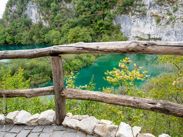 Fototapeta Wooden rail fence in front of teal blue lake in the Plitvice Lakes District, Croatia