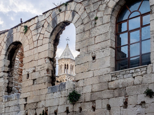 Fototapeta Ancient tower appears through arched stone window in wall surrounding Split, Croatia. 