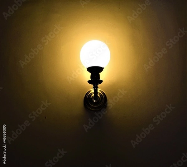 Fototapeta Lighted wall lamp in a dark room. Lights on. Concept background. Copy space.