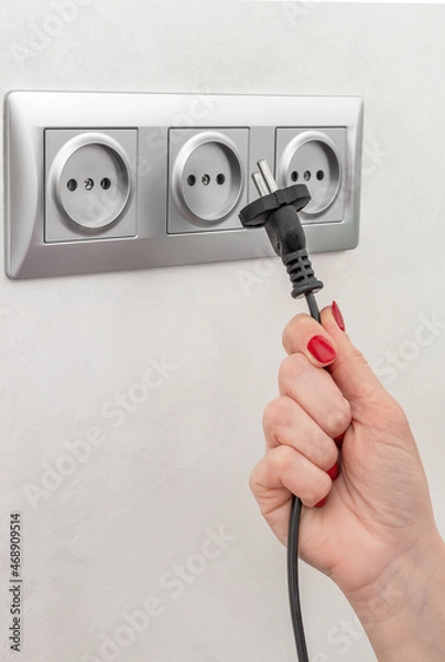 Fototapeta Hand holding plug near socket.