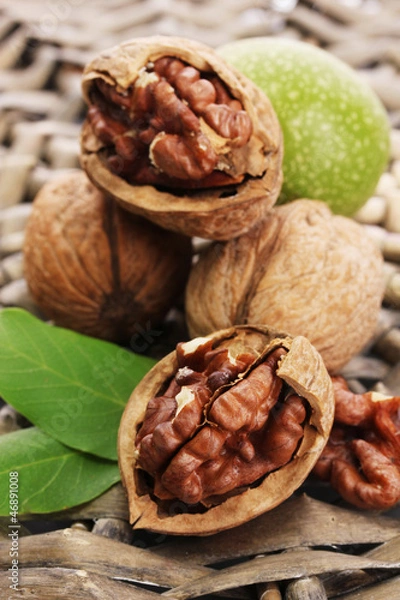 Fototapeta walnuts with green leaves, on  wicker background