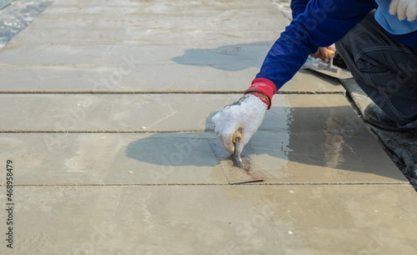 Fototapeta Motion blur white cloth gloves of workers are holding the trowel to smooth the cement face on floor in construction area.