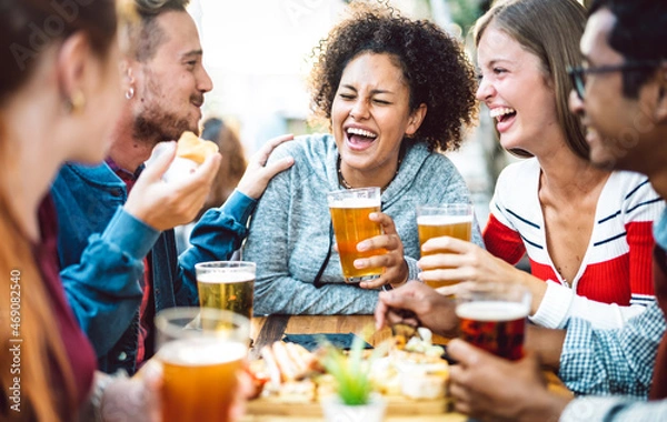 Fototapeta Multiracial friends drinking beer at brewery pub garden - Genuine friendship life style concept with guys and girls enjoying happy hour food together at open air bar dehor - Warm vivid filter