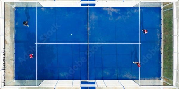 Obraz View from above, stunning aerial view of some people playing on a blue padel court. Padel is a mix between Tennis and Squash. It's usually played in doubles on an enclosed court.