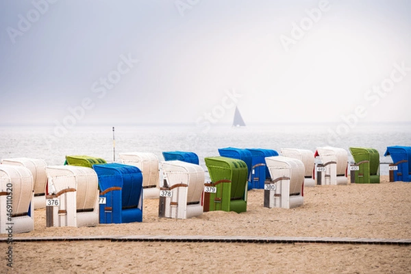 Fototapeta Green, blue and white strand baskets on the North Sea coast on the island of Föhr in hazy weather