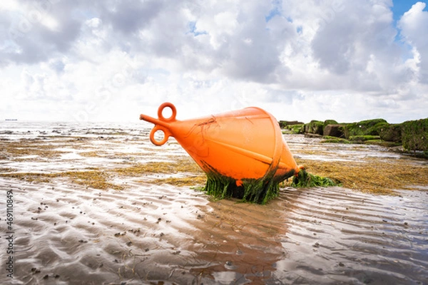 Fototapeta A bright red buoy lies on the mudflat in Dagebüll in Schleswigholstein at low tide