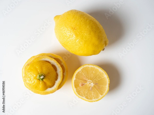 Fototapeta Close-up of a cut and whole lemon lying on a white background. isolated fruit. Sour yellow fruit full of vitamins. Top view, flat lay