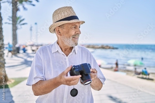 Obraz Senior man smiling confident wearing summer hat using camera at seaside