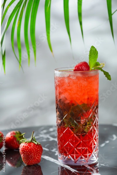 Fototapeta strawberry mojito with mint leaf on marble table. fresh drinks with strawberry and tropic branch on background