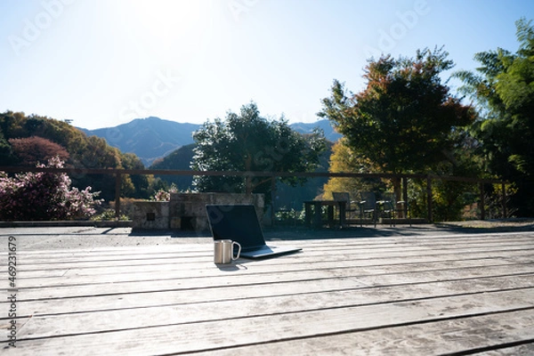 Fototapeta リモートワークなどに使いやすいウッドデッキにパソコンとコーヒーを置いたイメージ