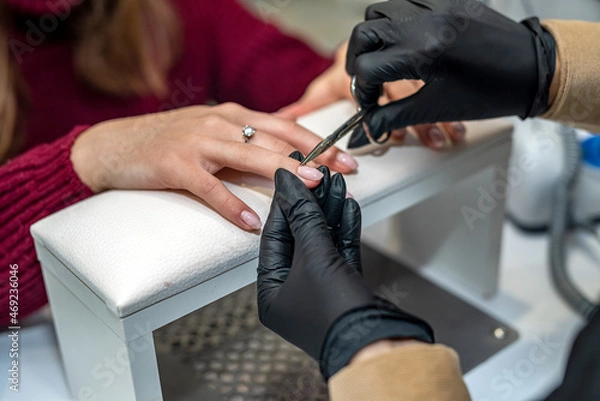 Fototapeta in salon nail specialist makes a gel varnish coating for a regular client during a pandemic.