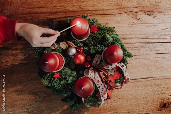 Fototapeta Lighting the first candle of Advent Wreath on the first Advent Sunday counting four weeks untill Christmas. Old swiss tradition in December to celebrate Advent time. View from above.
