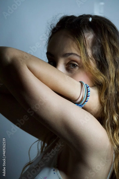 Obraz Woman looking at camera while posing with hands on her neck over an isolated background.