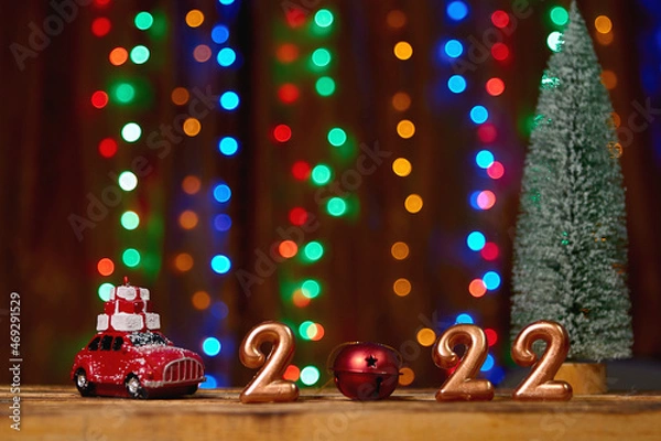 Fototapeta Holiday background  Numbers of year 2022 made by gold candles on bokeh festive sparkling background. celebrating New Year holiday, close-up. Space for text