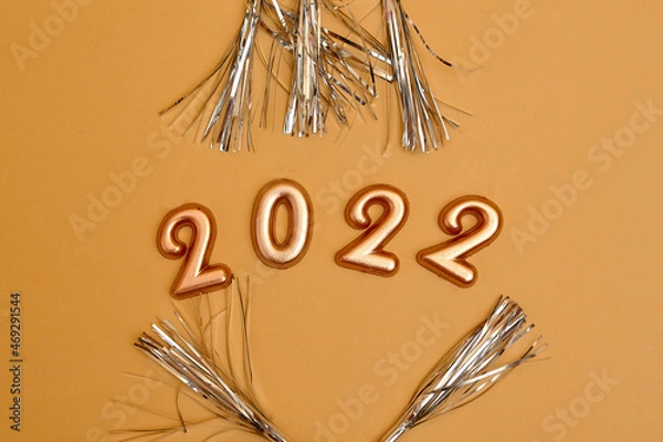 Fototapeta Holiday background  Numbers of year 2022 made by gold candles on bokeh festive sparkling background. celebrating New Year holiday, close-up. Space for text