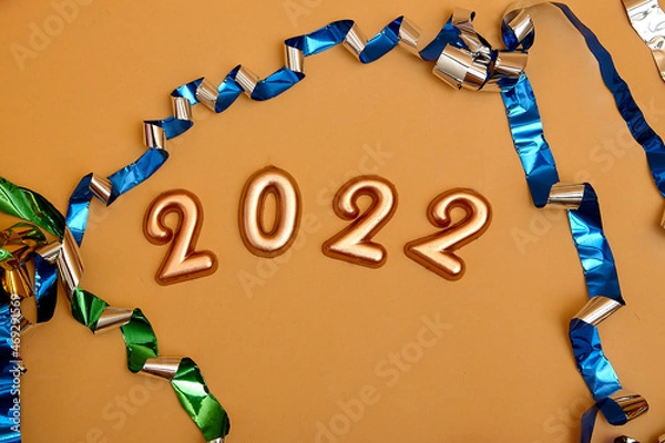 Fototapeta Holiday background  Numbers of year 2022 made by gold candles on bokeh festive sparkling background. celebrating New Year holiday, close-up. Space for text