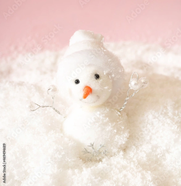 Obraz White snowman in snow smiling behind pastel pink background. Minimal Christmas and winter holidays happy concept.