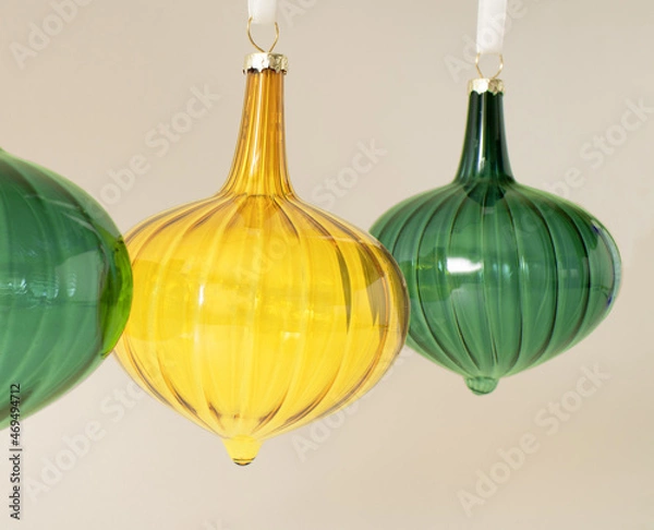 Fototapeta Christmas vintage glass ornaments in vivid yellow and green color hanging on the white rope behind pastel beige background. Winter holidays and New Year composition. Retro 80s or 90s aesthetic.