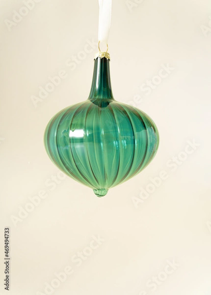 Fototapeta Christmas vintage green glass ornament hanging on white rope behind pastel beige champagne colour background. Minimal winter holidays and New Year concept. Retro 80s or 90s aesthetic.