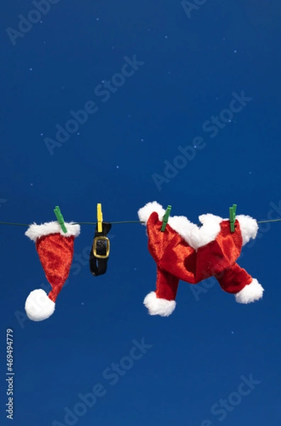 Fototapeta Christmas composition made of Santa's Claus sparkle red clothes hanging on rope behind night blue sky with stars. Winter holidays and New Year idea.