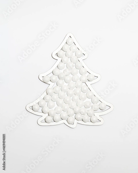 Fototapeta Christmas tree shape frame filled with snow sparkle balls ornaments against white background. Minimal winter holidays and New Year layout.