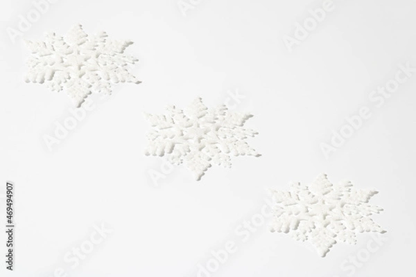 Obraz Christmas creative pattern made of white snowflakes with glitter on white table. Winter holidays and New Year monochrome aesthetic background.