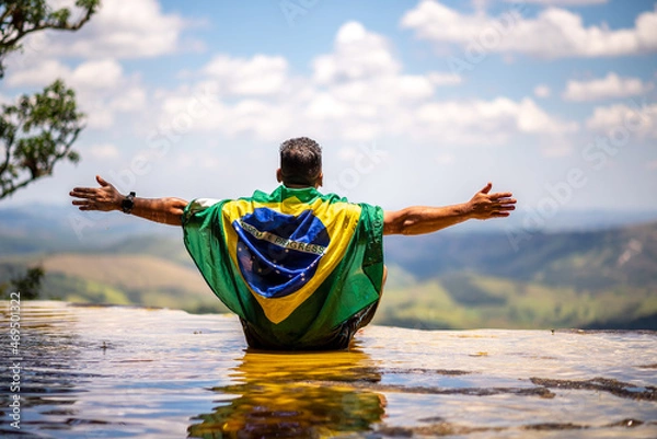 Fototapeta Man with Brazilian flag looking at the horizon. Top of Janela do Ceu Waterfall in Parque Estadual do Ibitipoca (Ibitipoca State Park), Minas Gerais, Brazil
