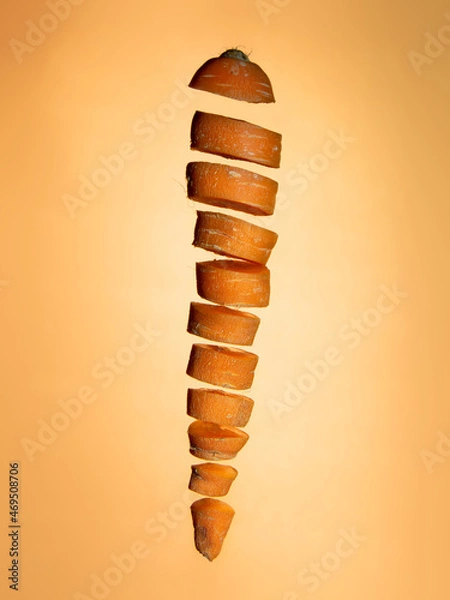 Obraz Sliced floating carrot on orange background