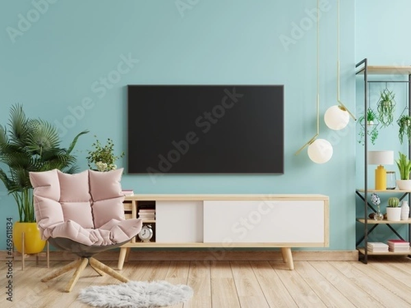 Fototapeta Mockup a TV wall mounted with armchair in a living room with a blue wall.