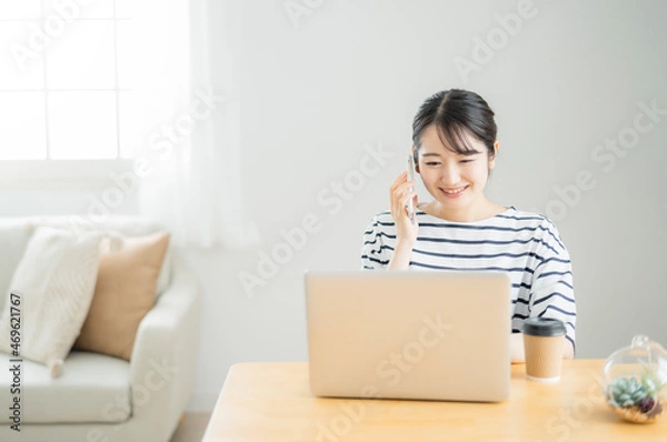 Fototapeta 家でテレワークする女性（スマホで電話）
